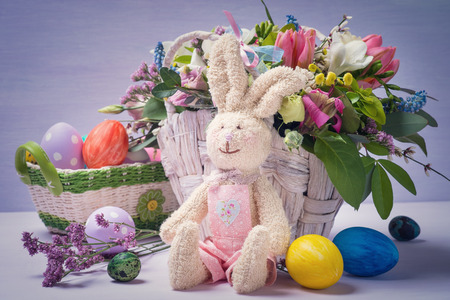 Rabbit with colorful Easter eggs and a full basket of decorative colorsの写真素材