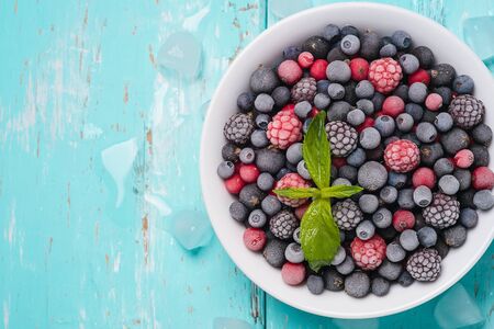 Frozen berries on a turquoise background with space for text, top viewの写真素材