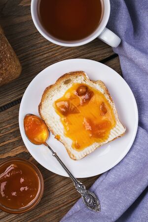 Bread with butter, apricot jam and a Cup of teaの写真素材