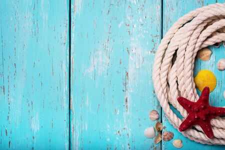 Seashells and rope on a wooden background with space for textの写真素材