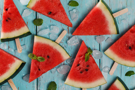 Pieces of ripe red watermelon with mint leaves on a wooden background. Top wievの写真素材