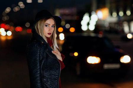 Portrait of a young beautiful girl. Model poses at night on a city streetの写真素材