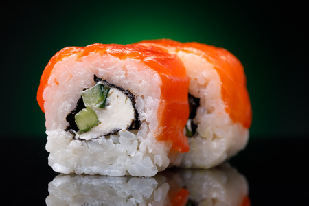 Rolls with red fish and cucumber on a black background. Japanese restaurant menu, close-upの写真素材