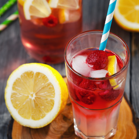 Glass of water with raspberries, slices of lemon and iceの写真素材