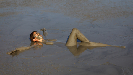 Girl takes useful procedures in the active mud volcano