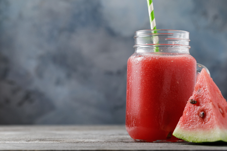 Smoothies cooked from a watermelon in a transparent jar on a wooden table with space for textの写真素材