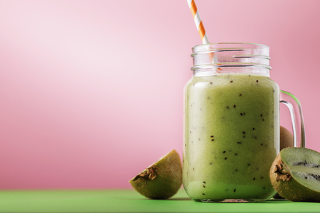 Smoothies cooked from ripe kiwi in a transparent jar with fruit with space for textの写真素材