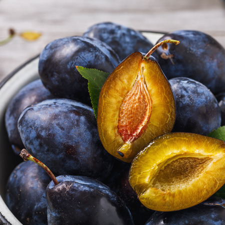 Full plate of ripe prune fruits on wooden table close-upの写真素材