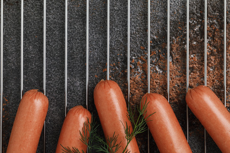 Few fresh sausages on a metal grill before baking with copy space, top viewの写真素材