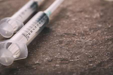 Empty syringes on a stone surface with copy space