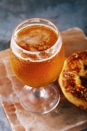 Full glass of fresh light beer with pretzel on a stone support close-upの写真素材