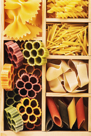 Set of different pasta in a wooden box, top view.の写真素材