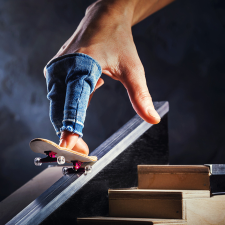 Riding a mini skateboard on a special track. Hand with fingerboard closeupの写真素材
