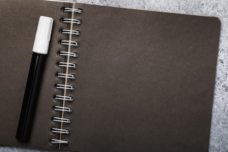 White pen and notebook for sketches with black sheets with copy space, top viewの写真素材