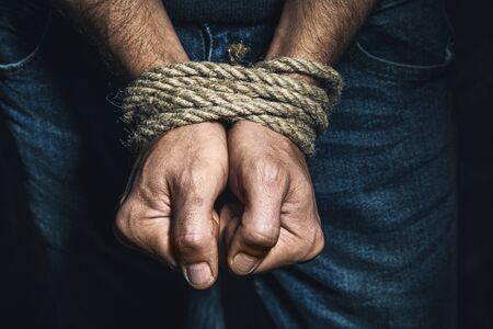 Men's hands tied with a rope, close-up. The concept of imprisonment in modern societyの写真素材