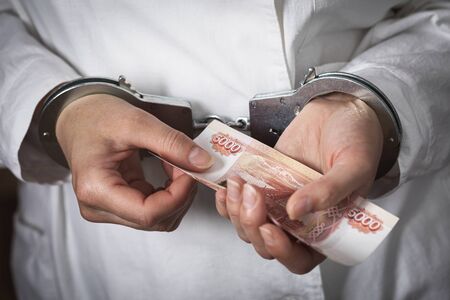 Doctor with Russian money in handcuffs. The concept of corruption in medicine and bribery, close-up