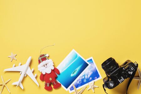 Toy airplane, photos and camera on a yellow background with copy space. Christmas Travel Planning Conceptの写真素材