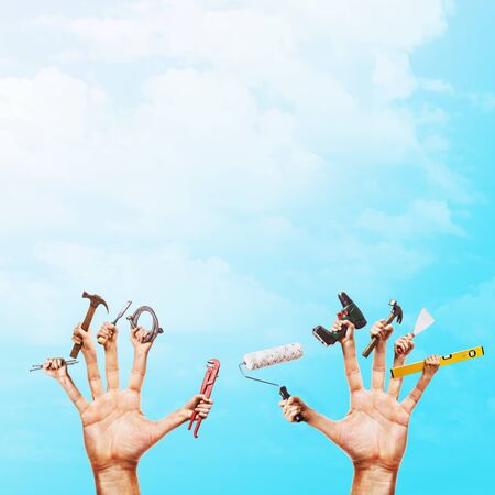 Various construction tools in hands on a blue sky background with copy space. Handyman concept