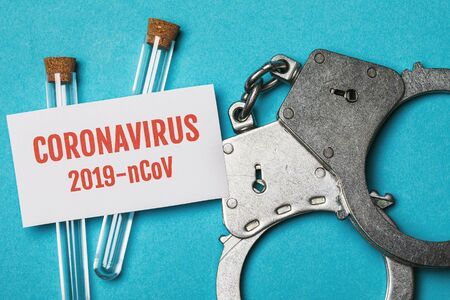 Medical flasks, handcuffs and paper with the inscription Coronavirus. The concept of punishment for...