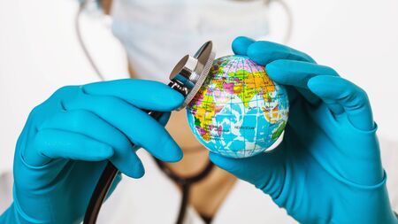 The doctor put a stethoscope to the globe. The concept of global healthの写真素材