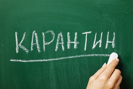 The inscription in Russian letters: Quarantine. On the blackboard, the teacher wrote the word quarantine. Seasonal Viral Disease Conceptの写真素材