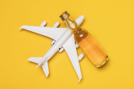 Airplane and bottle of whiskey on a yellow background, top view. Concept on the topic of drunkenness among pilots.の写真素材