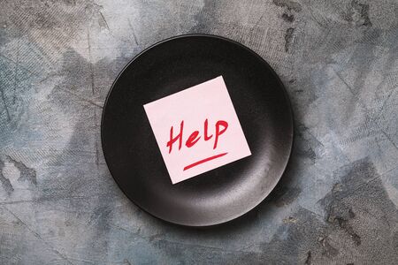 Note with text on black plate, top view. Concept of calling for help to the restaurant business due to the covid-19 pandemicの写真素材