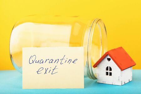 A note with text, an empty can and a toy house. Concept of Leaving the Quarantine Caused by the...