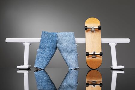 Fingerboard and jeans near a white metal railing. Board for riding on fingersの写真素材