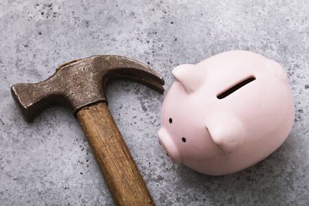 Pink piggy bank and hammer on the table, closeup. Crisis conceptの写真素材