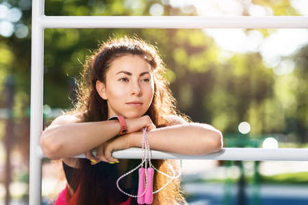 Portrait of a young beautiful girl with a skipping rope in her hands on the sports ground