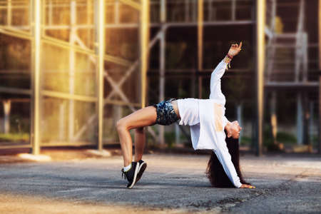 The girl dances on a street platform in the summer sunny eveningの写真素材