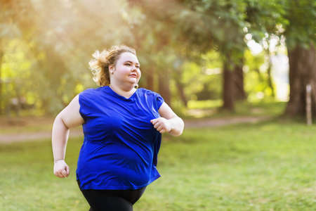 Young plus size blonde is jogging in the park on a summer sunny evening. Healthy lifestyle conceptの写真素材
