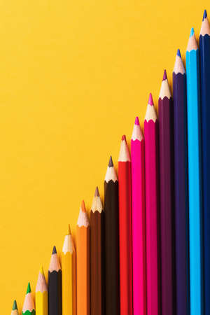 Colored pencils on yellow background, top viewの写真素材