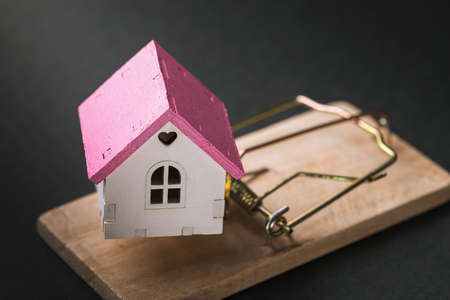 Small toy house in a mousetrap. Concept on the topic of housing traps and fraudulent real estate transactionsの写真素材