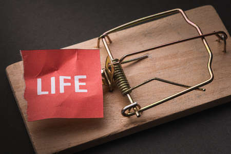 A piece of paper with text in a mousetrap. Concept on the topic of complex life in modern society.