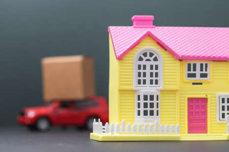A toy house and a car with a load on the roof, the concept of moving to another place of residence.の写真素材