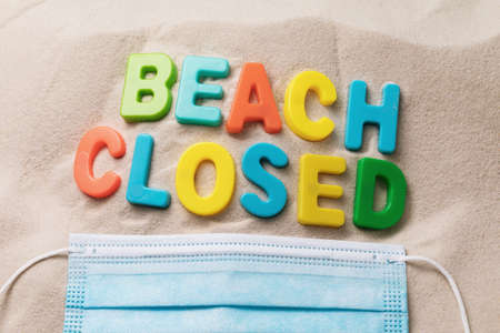 A message on the sand made of plastic letters and a disposable medical mask, a concept on the theme of a closed beach.の写真素材