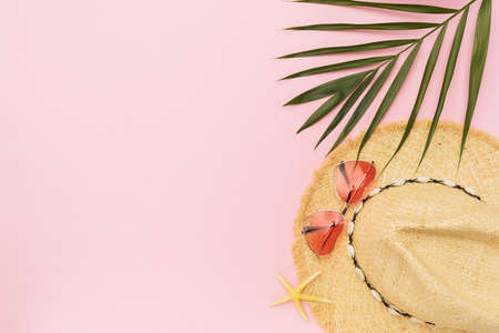 Ladies straw hat, sunglasses and palm leaf on pink background with copy space, summer background.の写真素材