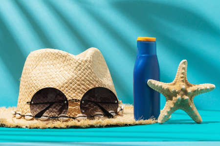 Womens straw hat, sunglasses, sunscreen and starfish on a colored background.の写真素材