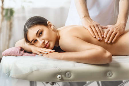 A young beautiful woman is in the salon at the reception of a masseur, resting during a therapy session.の写真素材