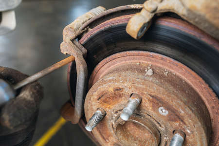 An auto mechanic grinds off rust on the brake discs before replacing the pads, close-up
