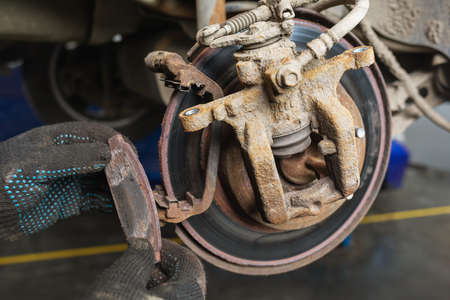 An auto mechanic removed a completely worn out brake pad, a concept on the timely replacement of car partsの写真素材