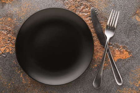 Empty black ceramic plate and silver cutlery, top view, food backgroundの写真素材