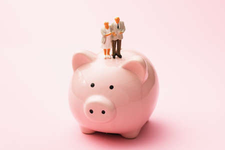 Toy men made of plastic stand on a piggy bank, the concept of saving for old ageの写真素材