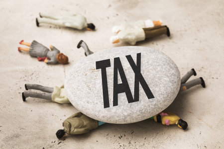A stone with an inscription lies on toy men made of plastic, the concept of taxes crushes people