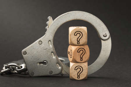 Handcuffs and wooden cubes with a question mark, guilt determination conceptの写真素材