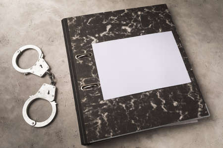 Folder with documents and handcuffs on the table, punishment concept, template for designersの写真素材