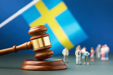 Judge gavel against the background of a blurry flag and toy plastic men, the concept of litigation in Swedenの写真素材