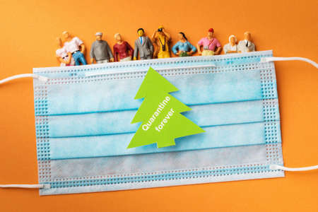 Plastic toy men, medical mask and a sticker with text on a colored background, the concept of...
